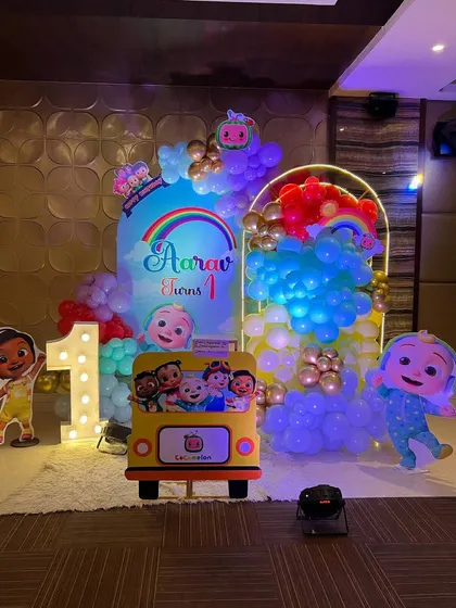This is a duplicate of ID 1, 68, 137, 226, 190, 213, 240, 250. A vibrant Cocomelon theme for a first birthday party. This setup includes a custom arched backdrop, a rainbow-colored balloon arrangement, and a life-sized cutout of the character JJ.