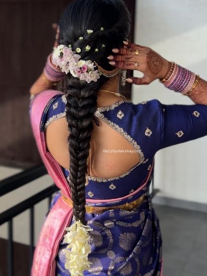 A neat and classic South Indian fishtail braid, adorned with fresh flowers along the top and a jasmine bunch at the end, perfect for a traditional event.