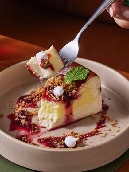 A forkful of our Burnt Basque Vanilla Bean Cheesecake. This dessert is all about contrast, with a molten lemon curd center, crunchy oatmeal crumble, and sweet macerated berries.