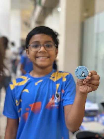 A proud player showing off his "I am a Squash Champ" badge from our community matchplay event. We love celebrating every player's participation and effort.