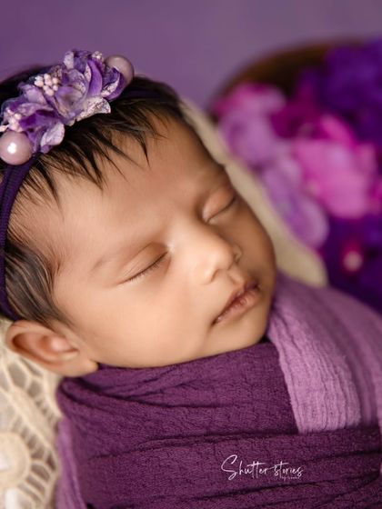 A close-up of the purple-themed shoot, focusing on the baby's face and the delicate floral headband.