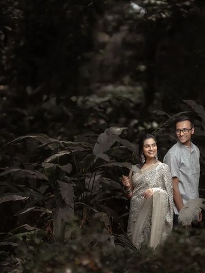 A wide shot of a couple in a dense, green location, creating a feeling of being in their own private world for their pre-wedding photos.