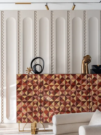 This custom console with a geometric wood inlay is a piece of functional sculpture. Set against a wall with subtle 3D paneling, it demonstrates our commitment to bespoke details that elevate a space beyond the ordinary.