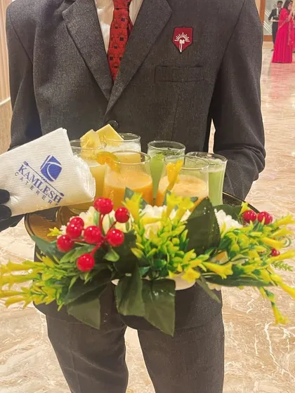 I believe in elegant service. Here, a member of my uniformed staff serves welcome juices on a beautifully decorated tray, complete with floral garnishes and branded napkins.