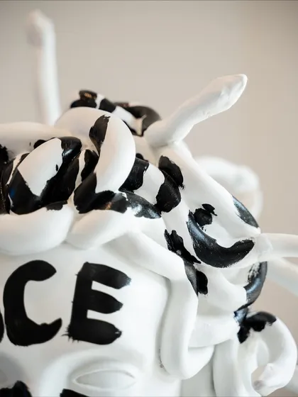 A detail of the snakes in Medusa's hair, rendered in white with bold black brushstrokes, adding to the graphic and powerful aesthetic.
