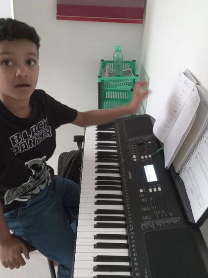 A young student looking excited during his keyboard lesson.