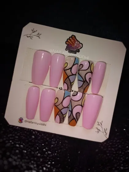 A retro-inspired abstract design in a custom press-on set. This features colorful, curved shapes outlined in black, paired with solid pastel pink nails.