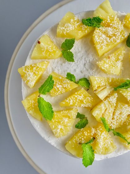 A top-down view of my Coconut Pineapple cake. The fresh pineapple chunks, mint leaves, and sprinkle of coconut create a tropical escape on a plate.