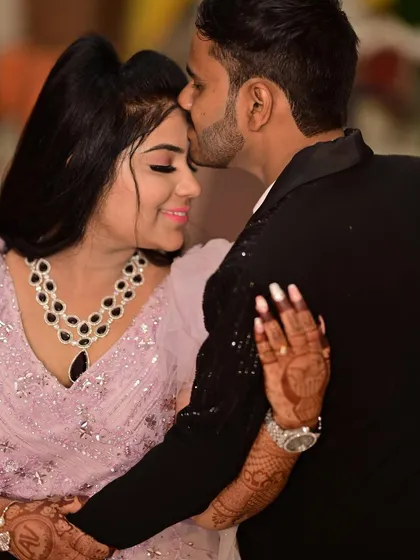 A close-up of a tender moment. This shot highlights the bride-to-be's beautiful makeup, henna, and the sparkling details of her pink engagement gown.