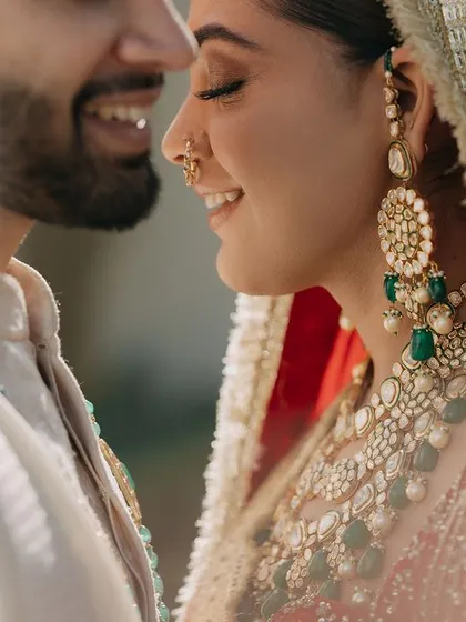 A joyful close-up of Anmol and Ashmeet. This shot captures their radiant smiles and the beautiful details of their wedding looks, highlighting the happiness of the moment.