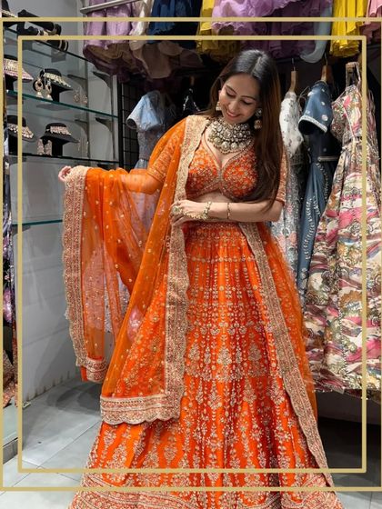 A client trying on a vibrant rustic orange lehenga in my store.