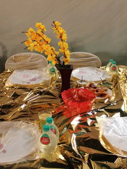 For a touch of opulence, we use golden tablecloths that shimmer under the lights. This setup, with neatly wrapped plates and bottled water, is ready for a grand celebration.
