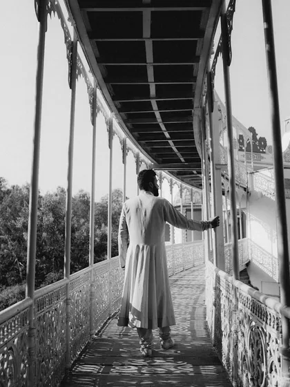 A dramatic black and white shot of the groom walking along a corridor at Lohagarh Fort, his traditional attire creating a timeless silhouette.