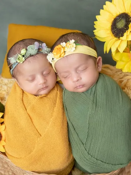 Two little sunflowers, born together. This photo showcases a beautiful setup for newborn twins, nestled together in a basket.