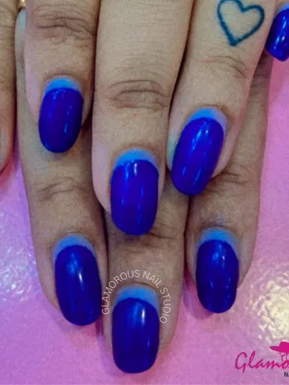 A sleek and modern design featuring a reverse French manicure in two shades of deep, glossy blue.