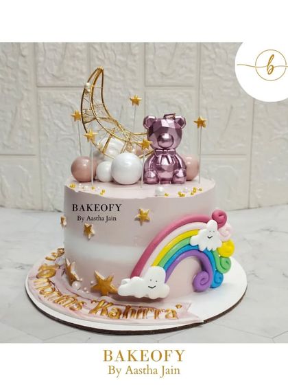 Twinkling under the moonlight, this choco-vanilla cake celebrates 10 months of pure joy with a chrome teddy bear, a rainbow, and stars.