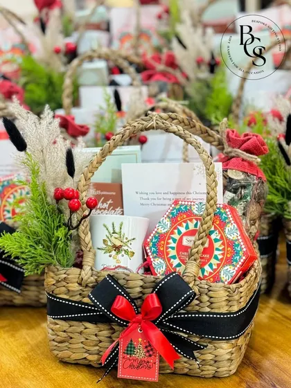 A charming Christmas basket filled with festive mugs, treats, and decorations. This is a perfect example of a warm and personal holiday gift for employees or clients.