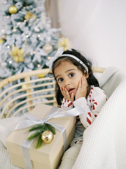 A little girl's surprised expression in front of a Christmas present. Capturing that holiday morning excitement.