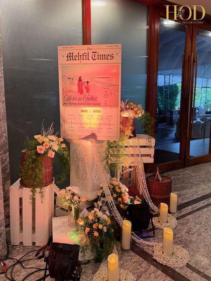 The full view of the "Mehfil Times" welcome sign setup, with rustic crates, candles, and floral baskets creating a charming and unique entrance feature.