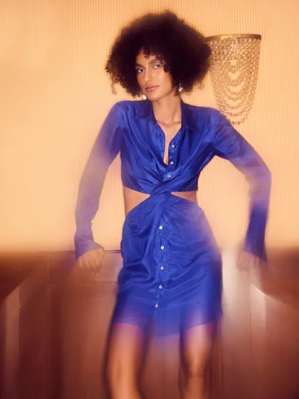 A solo shot featuring a blue cutout dress. The motion blur effect adds a dynamic, energetic feel, capturing the excitement of a night out.