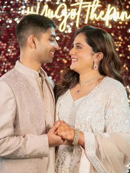 This couple's Sangeet look is pure elegance. The bride's makeup is soft and glowing, with her hair in romantic waves, perfectly matching the dreamy, fairy-light ambiance.