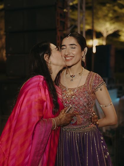A mother's love captured in a kiss. The mother of the bride wears a vibrant pink bandhani saree, a classic choice that we styled to feel both traditional and contemporary.