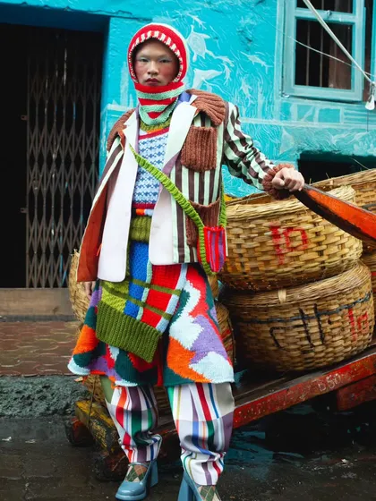 Another perspective from the "Kaleidoscope" series, this time interacting with local elements like wicker baskets. It grounds the high-fashion concept in a real-world setting, adding depth to the visual story.