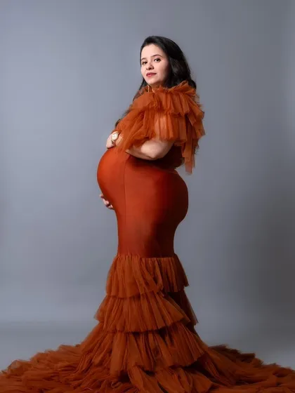 A profile view of our Bronze gown, showcasing the dramatic, tiered tulle skirt and how it accentuates the baby bump.