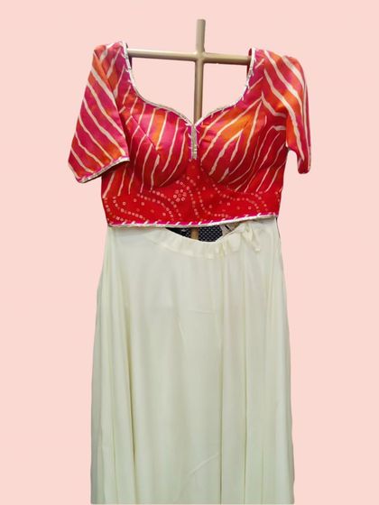 A detailed shot of the red bandhani and leheriya print blouse, showing the delicate mirror work along the neckline.