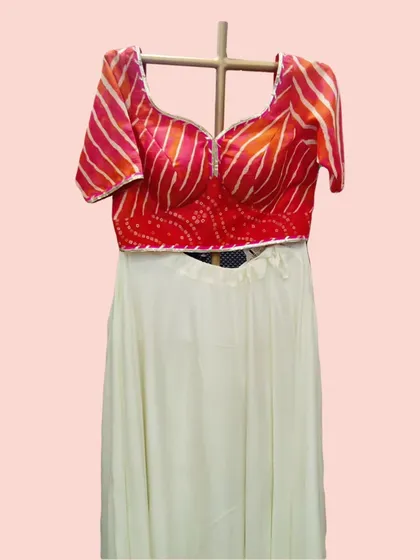 A detailed shot of the red and orange leheriya and bandhani print blouse, paired with the simple elegance of the white skirt.
