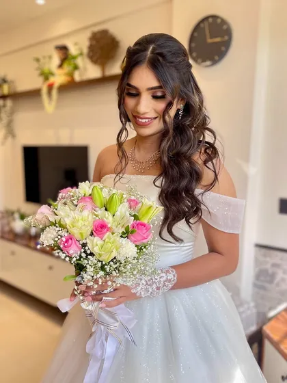 The bride holding her bouquet, her makeup looking fresh and radiant. The look is timeless and elegant.