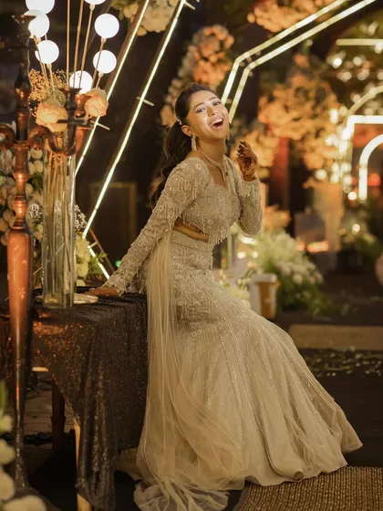 A joyful and candid bridal portrait. The bride's infectious laugh and relaxed pose by the beautifully decorated table show her vibrant personality.