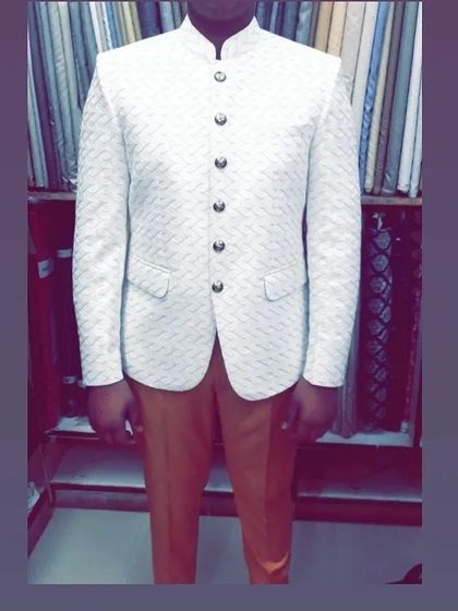 A client wearing a white self-patterned Jodhpuri jacket with contrasting dark buttons, paired with mustard trousers for a stylish, contemporary combination.