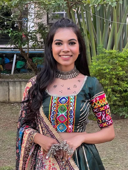 A vibrant Navratri look with a focus on a colorful, embroidered choli and traditional silver jewelry. The makeup is kept fresh and glowing.