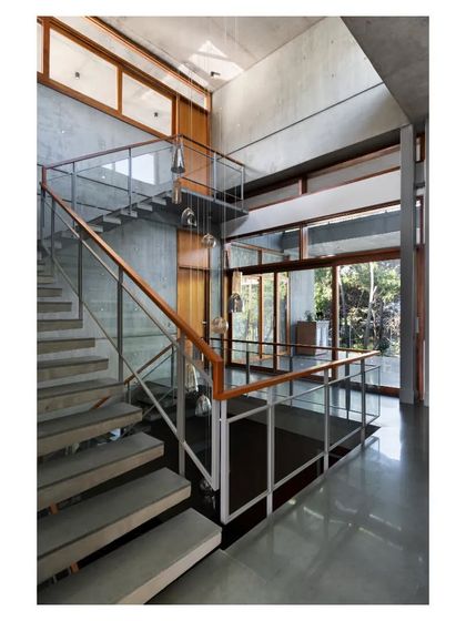 The central staircase is crafted from cantilevered concrete treads, appearing to float against the raw concrete wall, combining structural honesty with a sense of lightness.