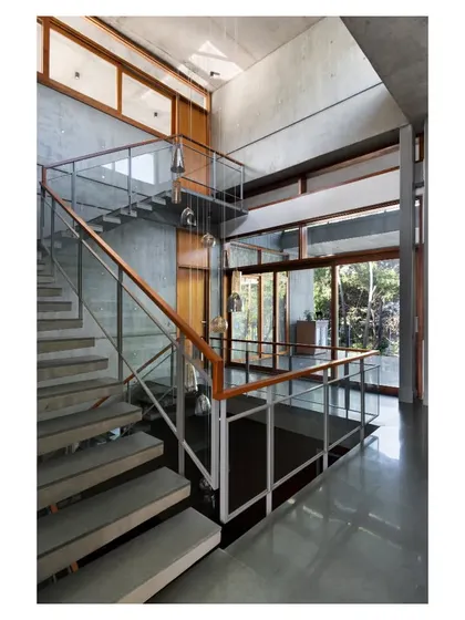 The central staircase is crafted from cantilevered concrete treads, appearing to float against the raw concrete wall, combining structural honesty with a sense of lightness.