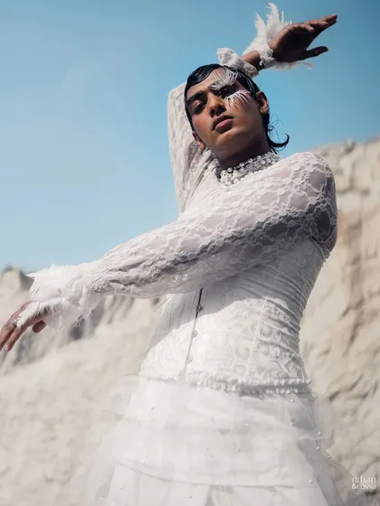 The model's pose mimics the shape of the feather makeup, creating a cohesive and artistic composition.