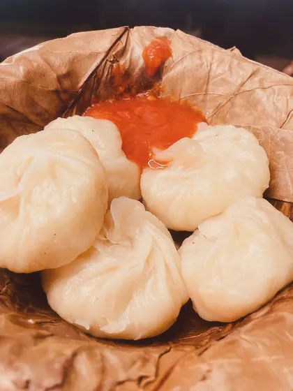Our freshly steamed vegetable momos served in an eco-friendly leaf bowl with a side of spicy red chutney. They are soft, juicy, and packed with flavor.