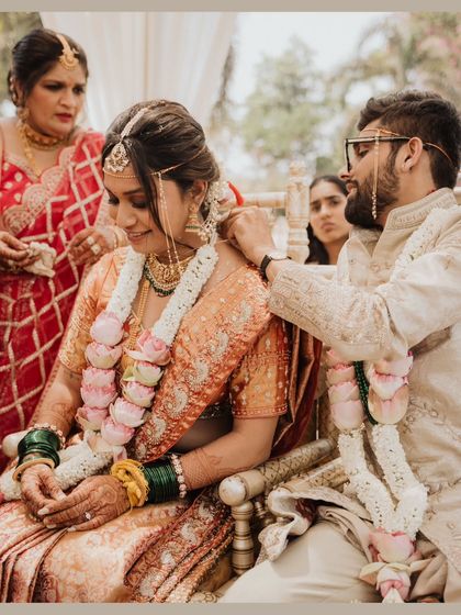 A tender moment during the ceremony, as the groom helps the bride with her necklace.