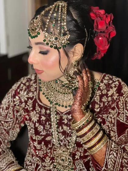 This bride's look is all about royal elegance. The deep maroon velvet, the contrasting green jewellery, and the red roses in her hair create a stunning combination.