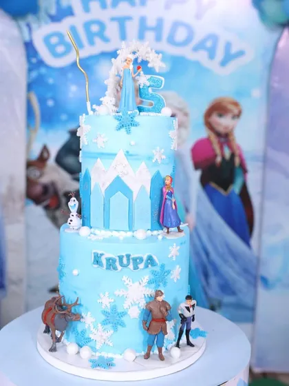 The two-tier Frozen cake as the centerpiece of a beautifully decorated party table.