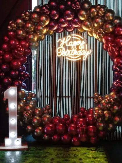 A moody and stylish ring backdrop with chrome red and gold balloons. Set against a striped curtain, this decoration for an 11th birthday has a very grown-up and cool vibe.