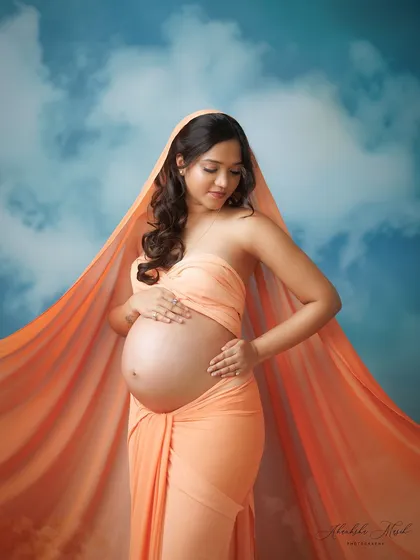 A serene and contemplative pose amidst the clouds, with the orange fabric creating a beautiful halo effect.