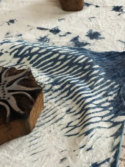 Another example of a traditional wooden block used for printing. The resulting fabric shows a classic pattern created with natural indigo dye, a testament to this timeless craft.