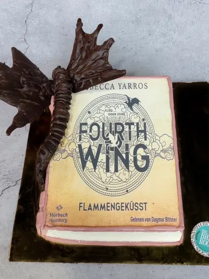 A cake for a book lover, designed as a copy of the fantasy novel 'Fourth Wing'. The edible book cover is paired with a hand-sculpted chocolate dragon wrapping around it.