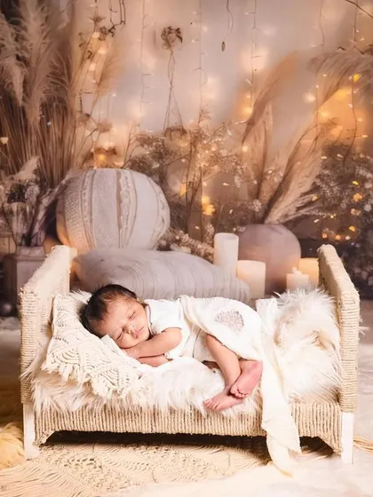 A wide shot of our dreamy, boho-inspired newborn setup. The tiny bed, pampas grass, and candles create a warm, glowing, and magical scene.
