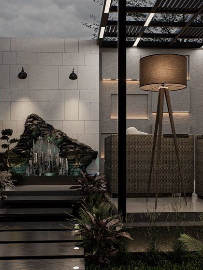 A natural rock water feature adds a touch of organic beauty to this modern terrace design. The pathway leads from the lounge area past the fountain, creating a journey through the different zones of the space.