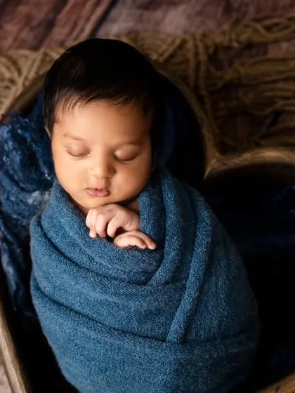 Tucked into a heart-shaped wooden bowl, this baby boy is wrapped in a beautiful shade of blue. This setup is perfect for showing just how much he is loved.