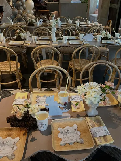 A long view of the kids' tables at the dragon-themed party, set with eco-friendly palm leaf plates, custom dragon cutouts, and simple floral centerpieces.
