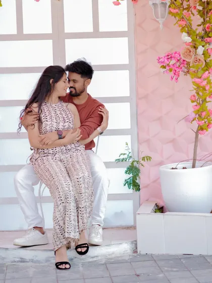 A tender moment against a romantic floral backdrop. The soft pink tones and the couple's gentle embrace create a dreamy and affectionate pre-wedding portrait.